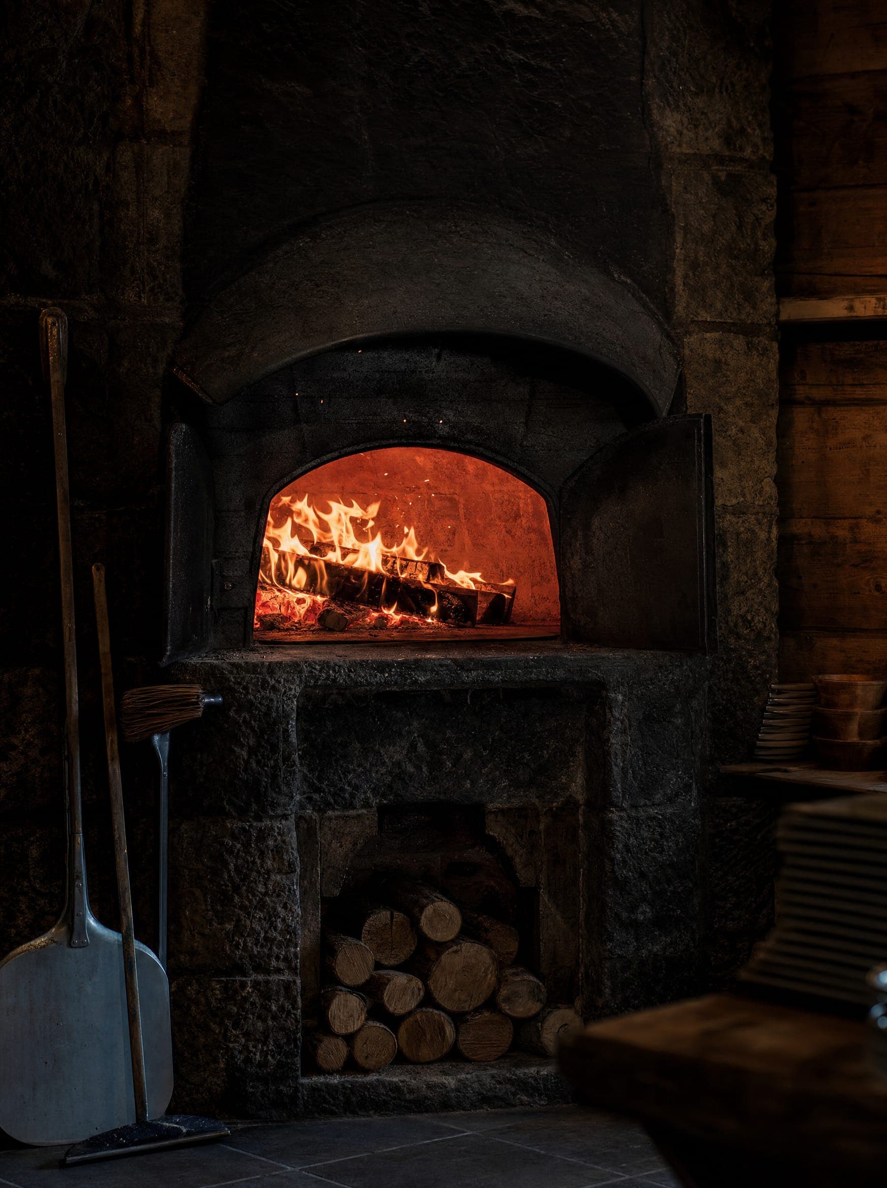 Der glühende Holzbackofen mit aufstiebenden Funken im dunklen Raum